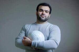 Portrait of a Man with a Soccer Ball A Strong and Confident Athlete Holding a White Soccer Ball Against a Grey Background photo
