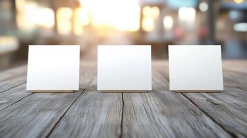 Three Blank White Squares On A Wooden Table Against A Blurred Background photo