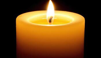 A single yellow candle flame burns brightly in the dark photo