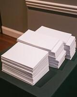 Stacks Of White Paper Rectangles On Green Surface In Front Of Gray Wall photo