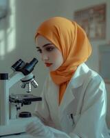 A Muslim Female Scientist Concentratedly Using a Microscope in a Laboratory Setting photo