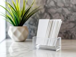 Stack Of Blank Business Cards In Transparent Holder With Potted Plant On Marble Surface photo