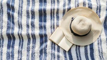 Straw Hat and Open Book on Striped Beach Blanket photo