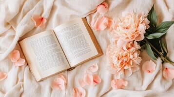 Open Book with Peach Peonies on Cream Blanket photo