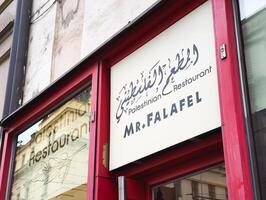 Prague, Czech republic - April 15, 2025 Mr. Falafel palestinian restaurant sign displaying arabic script and english words photo