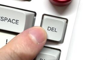 Finger presses the Delete button many times on the white keyboard, top view video