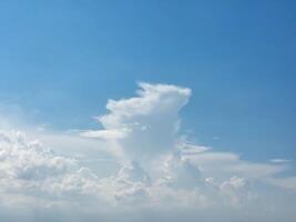 There are white cumulus clouds in the blue sky, one cloud looks like a running rabbit with ears photo