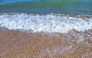 Beautiful azure sea with white foam and a beach on a clear sunny day. The concept of recreation. photo