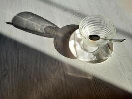 An empty ice cream bowl on the table with a spoon and shadows. View from above. photo