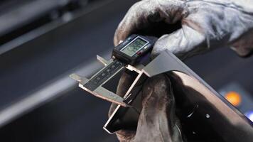 Gloved worker measuring metal component with digital caliper, Precision engineering process in industrial setting video