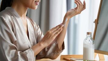 Applying moisturizer to arm in a well lit room during a self care routine while preparing for the day ahead photo
