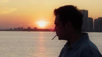 Man is Smoking Cigarette near the Sea in Sunset video
