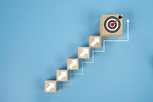 Arranges a wooden block staircase with target icon. Achieving goals and objectives or goal setting concept. photo