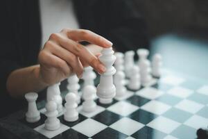 A close-up image of a hand holding a white chess piece, poised over a chessboard, symbolizing strategy and decision-making. photo