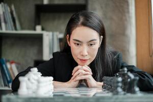 Woman intensely planning her next chess move in a contemporary office environment, showcasing strategic thinking. photo