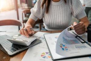 Professional woman reviewing financial documents and using a calculator at a desk, highlighting business and finance concepts. photo