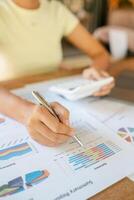 Close-up of a woman reviewing financial charts with a pen and calculator, focusing on data analysis and business strategy. photo