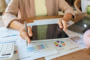 Professional woman using tablet to review financial charts and graphs at work desk, focusing on business strategy and analysis. photo