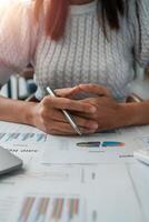 Close-up of a businesswoman reviewing financial documents with charts and graphs, highlighting data analysis and corporate strategy. photo
