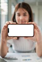 Young woman displaying a smartphone with a blank screen, ideal for mockups or app presentations in a modern office setting. photo