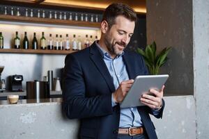 A man in a suit is using a tablet computer photo