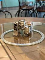 A round restaurant table with a glass lazy Susan holding condiments and a table number sign, with chairs in the background. photo