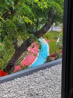 The picturesque view of a jogging track or running track can be admired through a window, having a beautiful tree in the foreground, enhancing the scenery photo