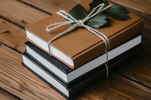 Rustic Stack of Brown, Black, and White Books with Green Leaves on Wooden Table photo