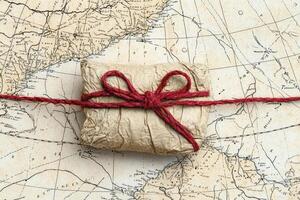 Rustic Wrapped Gift with Red Ribbon on Antique Map photo