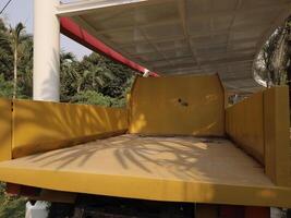 A Bright Yellow Empty Truck Bed Sitting in a Beautiful and Lush Green Environment photo
