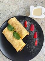 Rolled Pancakes with Strawberries. Crepes served with sweet condensed milk and berries photo
