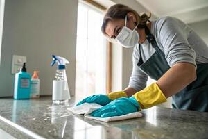 person wearing mask and gloves is cleaning countertop with disinfectant wipes, showcasing commitment to hygiene and cleanliness in modern home environment photo