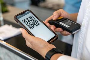person scanning QR code on smartphone at counter, showcasing modern technology and convenience. scene reflects seamless transaction experience photo