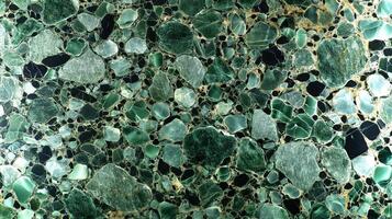 This green marble backdrop features an array of stones with organic shapes and colors, ideal for creating stylish and sustainable designs in various projects. photo