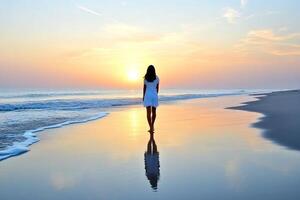 A woman walking on the beach at sunset photo