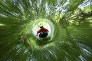 A man riding a skateboard through a tunnel of trees photo