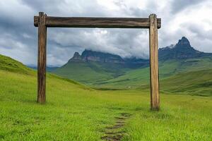 A wooden frame in a grassy field with mountains in the background photo
