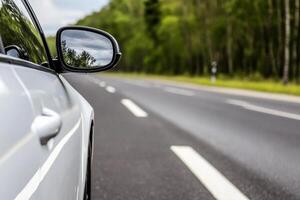 A car is driving down the road with its side mirror photo