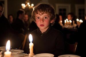 A young boy sitting at a table with candles photo