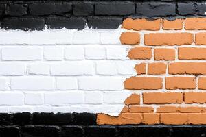 A brick wall with orange and white paint on it photo
