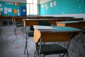 Empty desks in a classroom with a desk and chairs photo