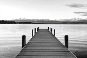 Black and white photograph of a dock extending into the water photo