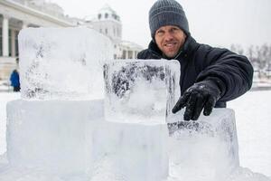 A man is holding up ice blocks in front of a building photo