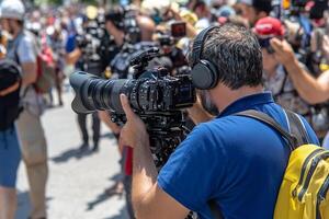 A man with a camera and a backpack is taking pictures of a crowd photo