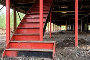 A red stairway in a building with a lot of dirt photo