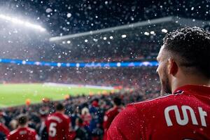 A man in a red shirt stands in front of a crowd photo