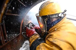 A man in yellow and red safety gear welding photo