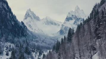 Snowy mountain landscape with towering peaks and forest during winter in a dramatic atmosphere photo