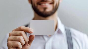 Man holding a blank card in front of a neutral background during a business setting or meeting photo