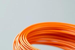 Orange wire coil twisted neatly for crafting projects or electrical use in a workspace photo